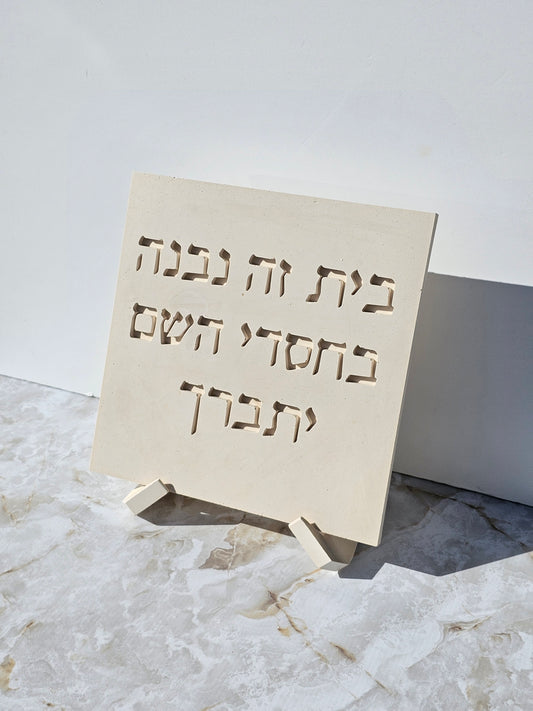 Angled view of stone-look Bayit Ze Nivnah Hebrew home blessing plaque on a stand, handmade Jewish decor by Gifts LA