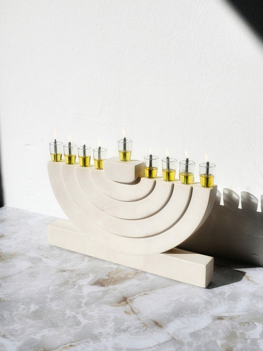 Handcrafted luxury stone-look menorah with layered arch form and glass oil cups, made for a modern warm elegant Hanukkah home