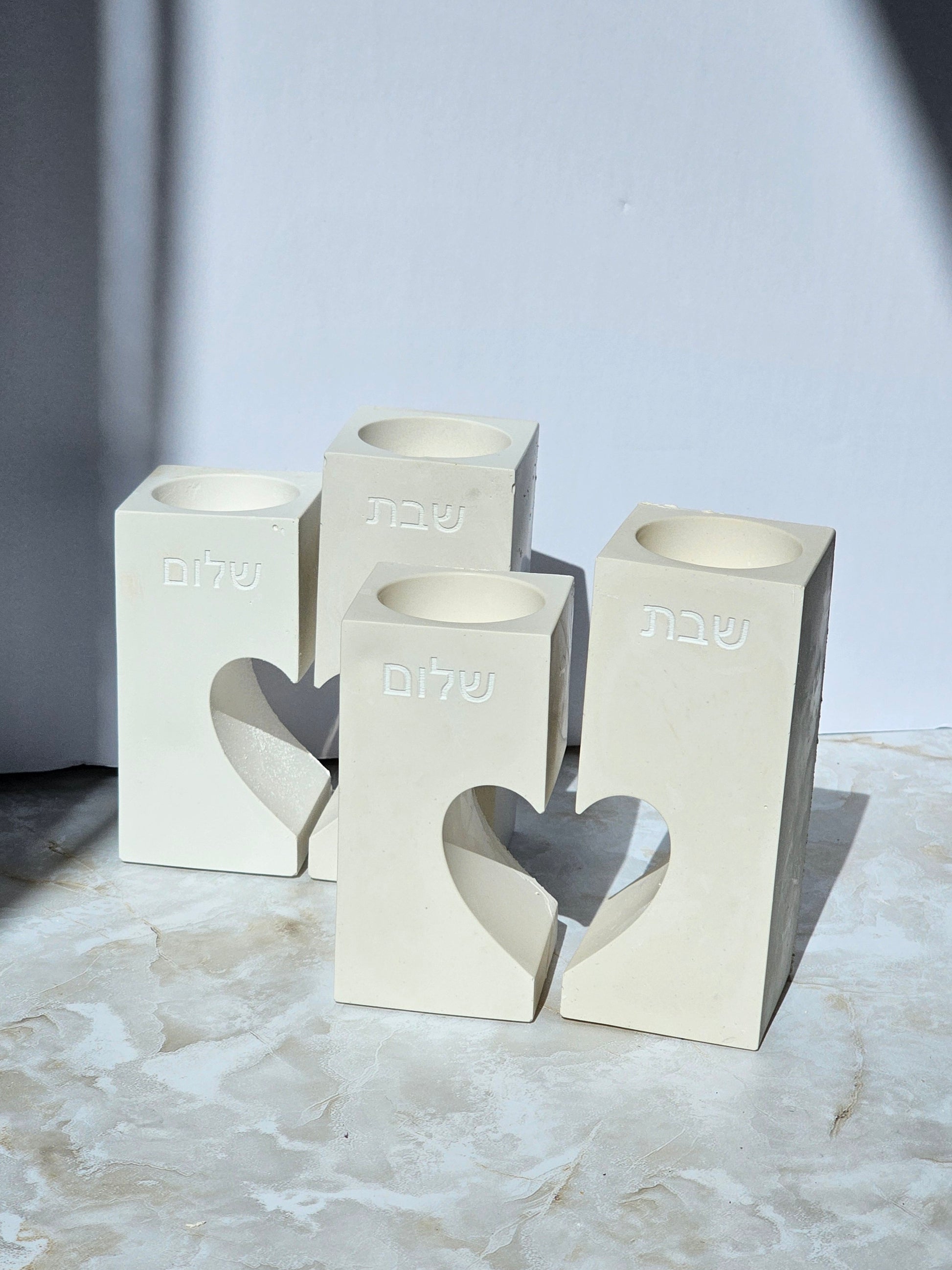 Modern concrete Shabbat candle holders with Hebrew engravings and heart cutout design, handmade in elegant natural finish