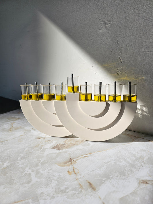 Elegant set of minimalist stone-look menorahs featuring curved lines and filled glass oil cups with black wicks